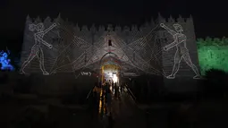 Orang-orang berjalan di dekat gerbang Damaskus selama festival cahaya di kota tua Yerusalem, 28 Juni 2018. Dalam festival yang ke-10 ini, baik anak maupun dewasa bisa datang tanpa dipungut biaya. (AFP / Ahmad GHARABLI)