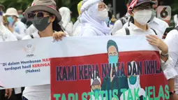 Massa dari Forum Komunikasi Nakes dan Non-Nakes Indonesia (FKHN Indonesia) membentangkan spanduk saat menggelar aksi di kawasan Patung Kuda, Jakarta Pusat, Kamis (22/9/2022). Sejumlah petugas gabungan berjaga di sekitar lokasi aksi dan awat berduri serta road barrier juga telah disiagakan. (Liputan6.com/Herman Zakharia)