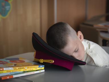 Seorang kadet muda tidur siang pada pelajaran pertama di sebuah sekolah kadet pada hari pertama sekolah di Kyiv, Ukraina, Senin, 2 September 2024. (AP Photo/Efrem Lukatsky)