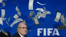 Ekspresi Presiden FIFA, Sepp Blatter, saat lembaran uang dollar terbang di sekitarnya. (AFP PHOTO/FABRICE COFFRINI)