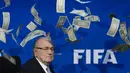 Ekspresi Presiden FIFA, Sepp Blatter, saat lembaran uang dollar terbang di sekitarnya. (AFP PHOTO/FABRICE COFFRINI)