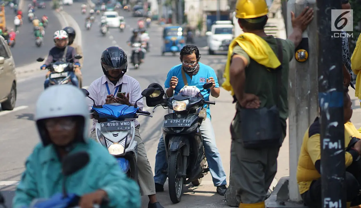 Pengendara motor mengoleskan pasta gigi ke wajahnya saat melintasi Jalan KS Tubun, Petamburan, Kamis (23/5/2019). Petugas Suku Dinas Bina Marga Jakarta Barat membagikan pasta gigi untuk mengurangi efek gas air mata yang digunakan untuk membubarkan massa aksi 22 Mei. (Liputan6.com/Immanuel Antonius)