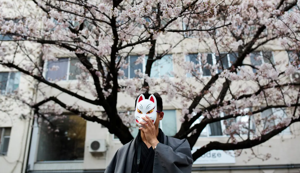 Seorang pria berpose dengan latar Bunga Sakura di kawasan Asakusa Tokyo, Kamis (6/4). Salah satu momen yang paling ditunggu pada musim semi di Jepang adalah mekarnya bunga sakura (cherry blossom). (AFP Photo/ Behrouz MEHRI)