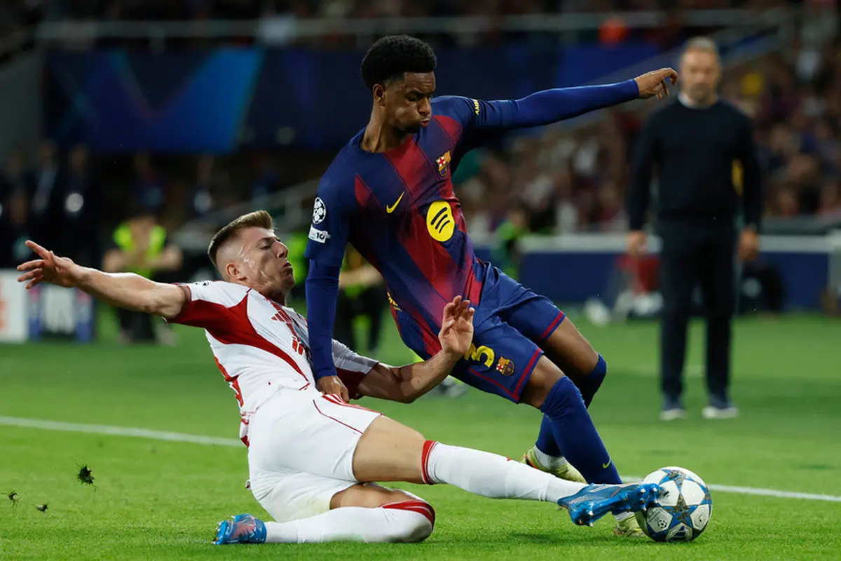 Pemain Olympiakos, Costinha (bawah), berusaha menghentikan pemain Barcelona, Alejandro Balde