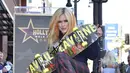 Penyanyi Avril Lavigne, memegang papan skateboard saat menghadiri upacara  penghargaan bintang Hollywood Walk of Fame di Los Angeles, Rabu (31/8/2022). Delapan nominasi Grammy Award dan delapan Juno Awards, termasuk Artist of the Year menjadi bukti bahwa Avril Lavigne pantas menerima bintang Walk of Fame. (Photo by Richard Shotwell/Invision/AP)