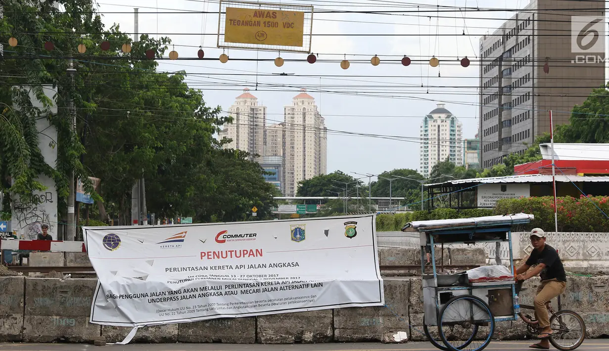 Pedagang melintas di perlintasan kereta api Jalan Angkasa Raya Kemayoran, Jakarta, yang ditutup dengan spanduk sosialisasi Kamis (26/10). Uji coba penutupan perlintasan kereta api itu dilakukan 13 hingga 27 Oktober 2017. (Liputan6.com/Immanuel Antonius)