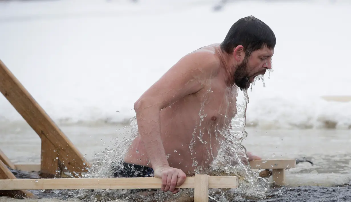 Penganut Kristen Ortodoks Rusia berenang di air es saat Epiphany di Desa Orlino, sebelah selatan Saint Petersburg, Jumat (19/1). Ribuan orang terjun ke sungai dan kolam es untuk membersihkan diri dengan air yang dianggap suci. (AP Photo/Dmitri Lovetsky)