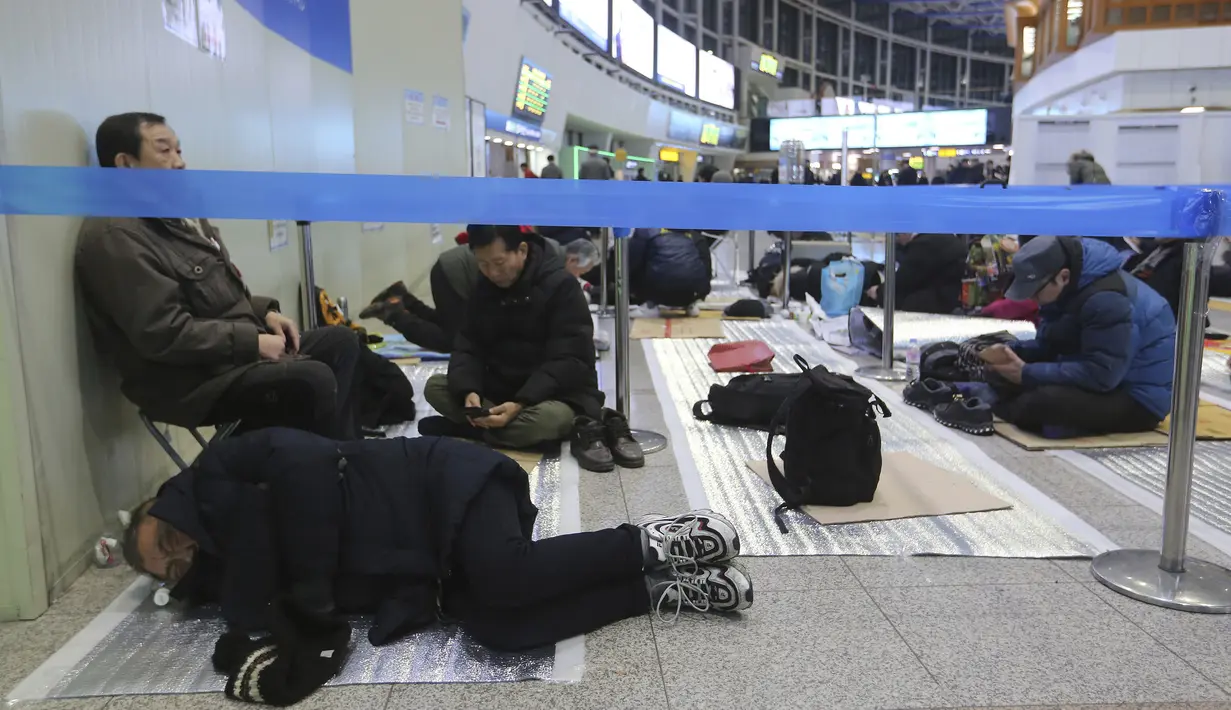 Seorang pria tidur ketika dia menunggu untuk membeli tiket kereta api untuk mudik ke kota asalnya selama liburan Tahun Baru Imlek, di Stasiun Kereta Api Seoul di Seoul, Korea Selatan, Selasa (7/1/2020). Tahun Baru Imlek jatuh pada 25 Januari tahun ini. (AP Photo/Ahn Young-joon)