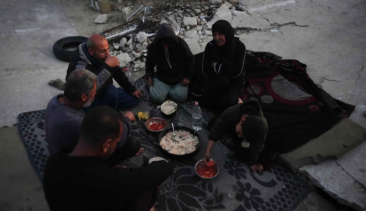 Mereka memasak dan makan di antara puing-puing bangunan, mencerminkan krisis kemanusiaan yang masih berlanjut. Tampak dalam foto, keluarga Suleiman berbuka puasa di bulan suci Ramadan di samping reruntuhan masjid, tempat mereka saat ini berlindung di Deir al-Balah, Jalur Gaza, Jumat 6 Maret 2026. (AP Photo/Abdel Kareem Hana)