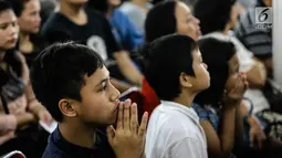 Sejumlah jemaat anak-anak mengikuti dengan khusyuk prosesi jalan salib di Gereja Katedral, Jakarta, Jumat (30/3). Rangkaian perjalanan Yesus yang divisualisasikan ini terdiri dari 14 peristiwa. (Liputan6.com/Faizal Fanani)