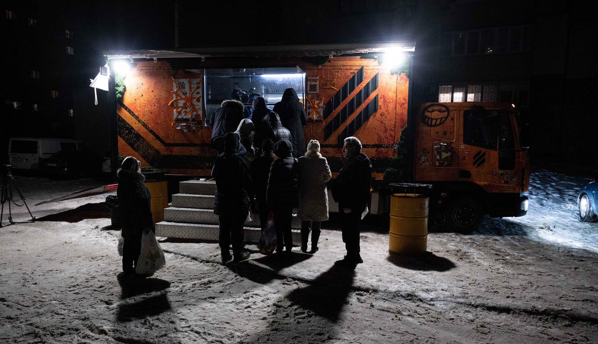 Warga mengantre di sebuah truk makanan milik the 3rd Separate Assault Brigade Angkatan Bersenjata Ukraina untuk mendapatkan makanan panas gratis bagi orang-orang di lingkungan perumahan yang rumahnya tanpa listrik setelah serangan udara Rusia berulang kali terhadap sektor energi negara itu di Kyiv, Selasa 27 Januari 2026. Gelombang serangan rudal dan pesawat nirawak (drone) besar-besaran Rusia yang menargetkan infrastruktur energi dan kawasan pemukiman di berbagai kota Ukraina, termasuk Kyiv dan Kharkiv, berimbas pada krisis energi. (AP Photo/Danylo Antoniuk)