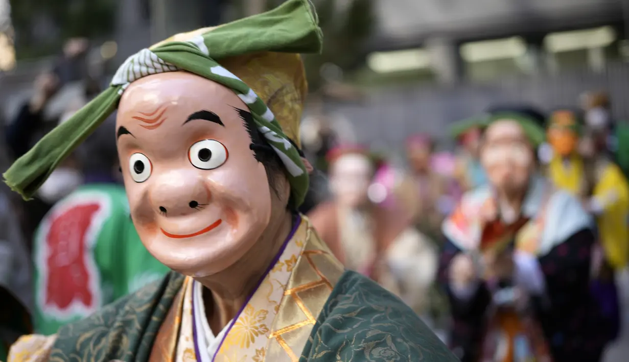 Seniman yang mengenakan topeng badut tradisional Jepang berbaris selama di kuil Kotohiragu di distrik bisnis Toranomon, Tokyo, Selasa (10/1/2023). Selain mengenakan topeng tradisional, para seniman tersebut juga mengenakan pakaian tradisional khas Negeri Matahari Terbit tersebut. (AP Photo/Eugene Hoshiko)