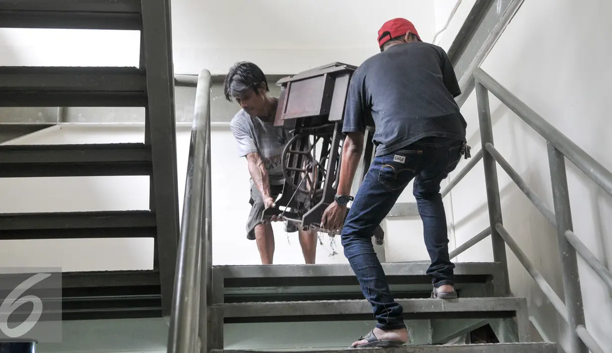 Dua orang pria memindahkan mesin jahit di Tempat Penampungan Sementara (TPS), Manggarai, Jakarta, Selasa (4/10). Pedagang Pasar Rumput mulai tempati kios TPS Pasar Jaya Manggarai. (Liputan6.com/Yoppy Renato)