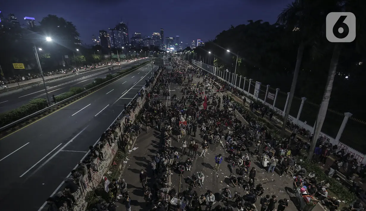 Mahasiswa dan elemen buruh bertahan hingga malam saat aksi di depan Gedung DPR/MPR/DPD, Jakarta, Kamis (16/7/2020). Dalam aksinya, mereka menolak pengesahan RUU Cipta Kerja atau Omnibus Law yang saat ini sedang dibahas DPR bersama pemerintah. (Liputan6.com/Johan Tallo)