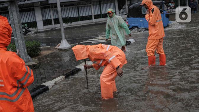 Petugas memeriksa genangan air di Jalan Medan Merdeka Timur, Jakarta, Jumat (24/1/2020). Hujan deras yang mengguyur Jakarta sejak pagi tadi mengakibatkan genangan air di Jalan Medan Merdeka Timur. (Liputan6.com/Faizal Fanani)