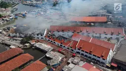 Foto udara menunjukkan petugas pemadam kebakaran memadamkan sisa api yang membakar Museum Bahari, Jakarta Utara, Selasa (16/1). Untuk menjinakan api, petugas pemadam kebakaran mengerahkan 21 unit mobil pemadam. (Liputan6.com/Arya Manggala)