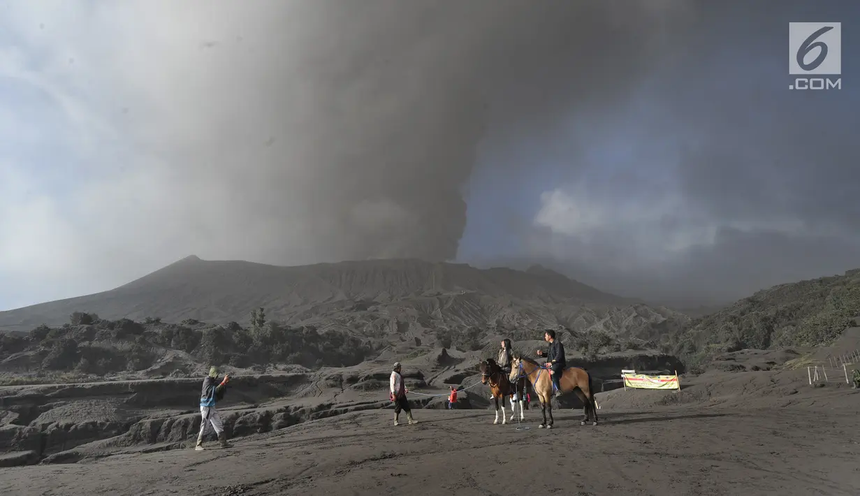 Wisatawan menunggang kuda dengan latar belakang Gunung Bromo yang menyemburkan abu vulkanis di Probolinggo, Jawa Timur, Selasa (26/3/2019). Aktivitas vulkanis Gunung Bromo masih berada di level II waspada, meski sedang mengalami erupsi pada beberapa hari belakangan ini. (merdeka.com/Arie Basuki)