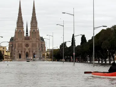 Warga menggunakan perahu saat melihat kondisi banjir di depan Basilika Lujan, Argentina, Rabu (12/8/2015). Lebih dari 20.000 orang telah dievakuasi setelah hujan lebat di akhir pekan lalu yang menyebabkan sungai naik dan banjir. (REUTERS/Marcos Brindicci)