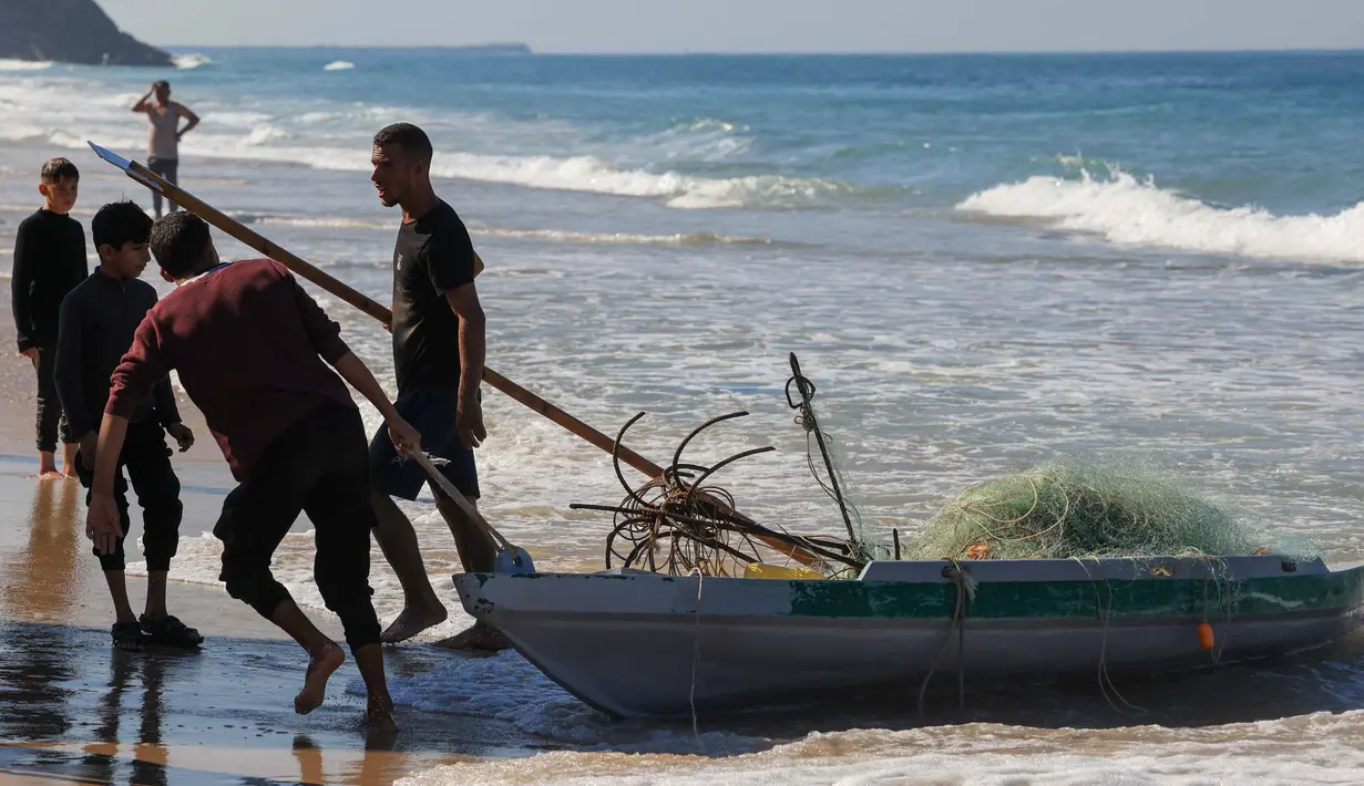 Nelayan Palestina menarik perahu mereka di pantai di Deir el-Balah, di Jalur Gaza Tengah pada 30 November 2023. (Mahmud Hams/AFP)