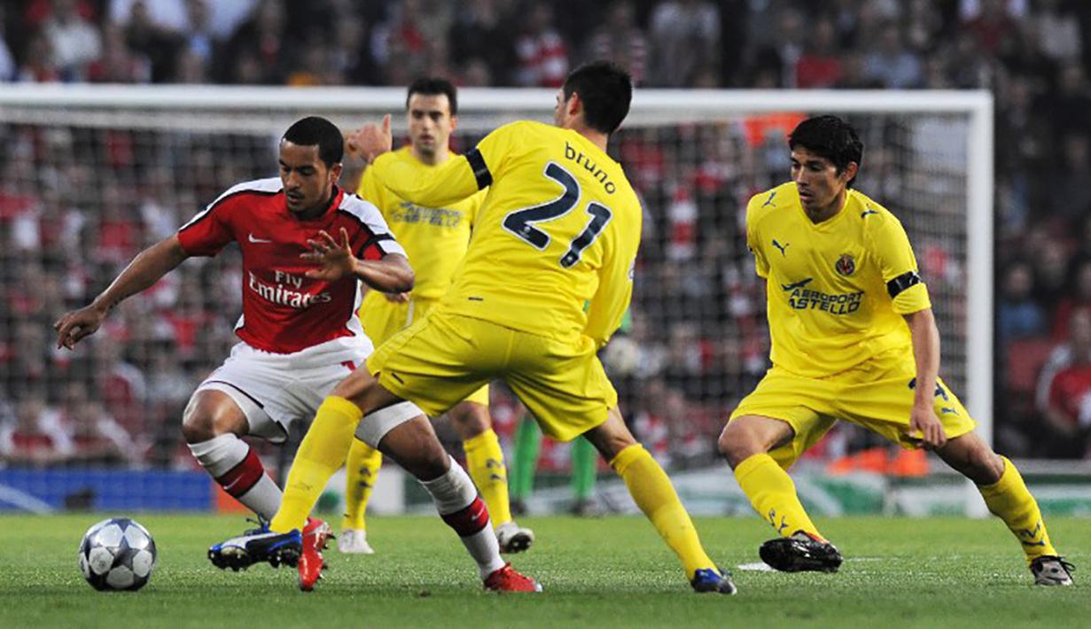 Pemain Arsenal, Theo Walcott dikepung pemain Villareal pada laga Liga Champions di Stadion Emirates, Inggris, Rabu (15/4/2015). Sementara itu kemampuan dribbling Walcott pada game FIFA 16 hanya mencapai angka 81. (AFP Photo/Carl de Souza)