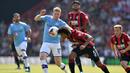 Gelandang Manchester City, Kevin De Bruyne, berebut bola dengan bek Bournemouth, Nathan Ake, pada laga Premier League 2019 di Stadion Vitality, Minggu (25/8). Manchester City menang 3-1 atas Bournemouth. (AFP/Glyn Kirk)
