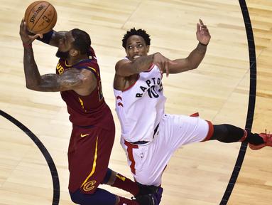 Pemain Cleveland, LeBron James (23) melakukan lay up saat diadang pemain Raptors, DeMar DeRozan (10) pada laga NBA playoffs Eastern Conference semifinal di Air Canada Centre, (1/2/2018). Cavaliers menang 113-112. (Frank Gunn/The Canadian Press via AP)