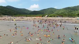 Orang-orang menikmati waktu senggang di sebuah resor pantai di Zhoushan, Provinsi Zhejiang, China timur (3/8/2020). Warga China menghabiskan waktu senggang dengan beraktivitas bermain air saat musim panas. (Xinhua/Yao Feng)