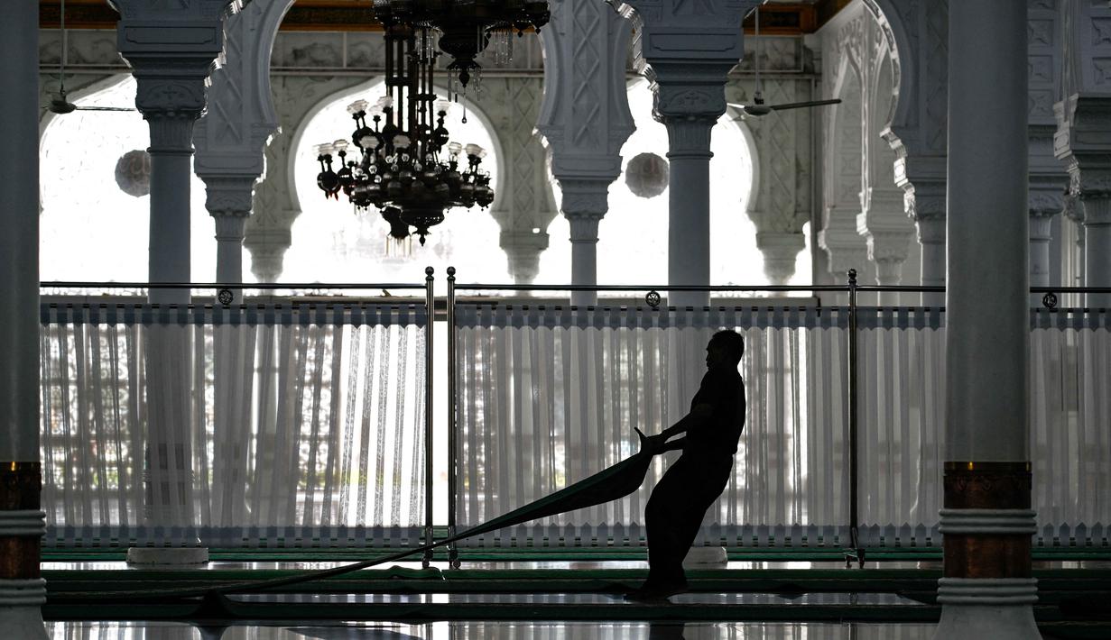 Beberapa pekerja terlihat sibuk menyiapkan serta membersihkan area yang akan digunakan umat Muslim untuk menjalankan salat tarawih. Tampak dalam foto, seorang pekerja menyiapkan karpet untuk salat tarawih pertama pada bulan suci Ramadan 1447 Hijriah di Masjid Agung Baiturrahman, Banda Aceh, Rabu 18 Februari 2026. (CHAIDEER MAHYUDDIN/AFP)