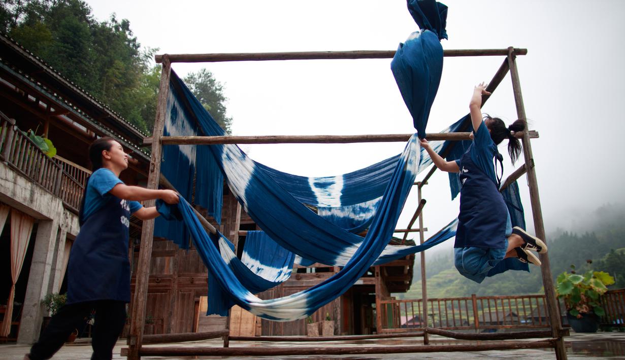 Dua orang perempuan menjemur kain di sebuah bengkel kerja di Desa Etnis Dong Fengdeng di Wilayah Rongjiang, Provinsi Guizhou, China pada 6 September 2020. Warga setempat memanfaatkan kondisi cuaca musim gugur yang mendukung untuk membuat kain tradisional kelompok etnis Dong. (Xinhua/Liu Xu)