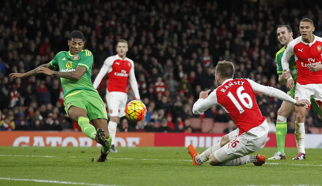 Pemain Sunderland, Patrick van Aanholt (kiri) melakukan tembakan saat dihadang pemain Arsenal  Aaron Ramsey pada lanjutan Liga  Premier Inggris di Stadion Emirates, London, Sabtu (5/12/2015). (AFP Photo/Ikimages) 