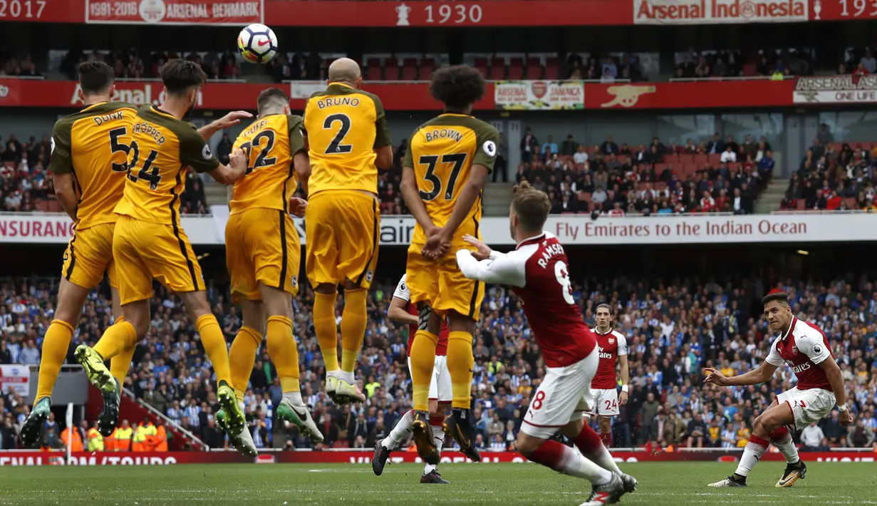 Pemain Arsenal, Alexis Sanchez (kanan) melakukan tendangan bebas saat melawan Brighton pada lanjutan Premier League di Emirates Stadium, London, (1/10/2017). Arsenal menang 2-0. (AFP/Adrian Dennis)