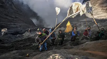 Warga menggunakan jaring untuk menangkap sesajen yang dilemparkan oleh masyarakat Suku Tengger di kawah gunung Gunung Bromo sebagai bagian dari festival Yadnya Kasada di Probolinggo, Jawa Timur, Senin (5/6/2023). (Photo by Juni Kriswanto / AFP)