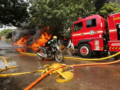 Pengemudi ojek online mendorong sepeda motor saat kebakaran melanda sebuah gudang di Jalan Kampung Bandan, Ancol, Jakarta Utara, Kamis (5/7). Kebakaran ini terjadi di dekat tempat wisata Kota Tua. (Kapanlagi.com/Budy Santoso)