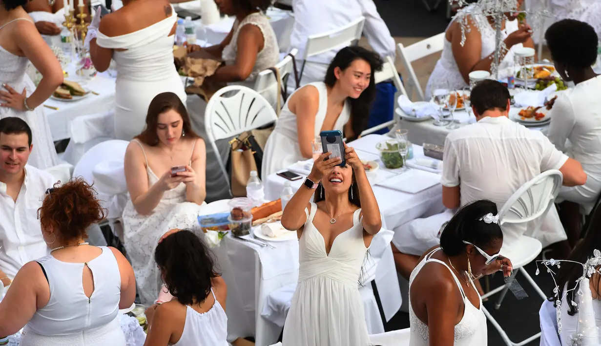 Sejumlah orang berpakaian serba putih menghadiri Diner en blanc (Dinner in White) di alun-alun Lincoln Center, New York, Selasa (22/8). Tahun 2015, sekitar 70 kota di lebih dari 35 negara telah atau akan mengadakan Diner en blanc. (TIMOTHY A. CLARY/AFP)