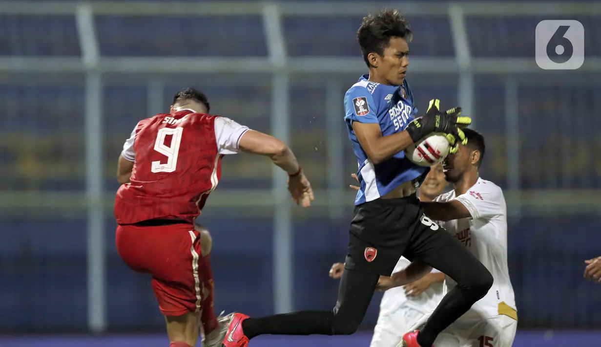 Kiper PSM Makassar Hilman Syah (kanan) mengamankan bola dari sundulan pemain Persija Jakarta Marko Simic dalam pertandingan babak penyisihan Piala Menpora 2021 di Stadion Kanjuruhan, Malang, Jawa Timur, Senin (22/3/2021). PSM Makassar menang dengan skor 2-0. (Bola.com/Arief Bagus)