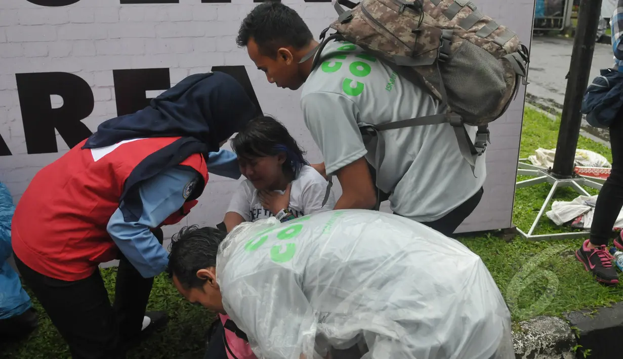 Petugas mengamankan seorang wanita yang pingsan saat mengantre untuk menonton konser One Direction, Senayan, Jakarta, Rabu (25/3/2015). Puluhan ribu orang rela mengantre untuk melihat konser One Direction. (Liputan6.com/Johan Tallo)