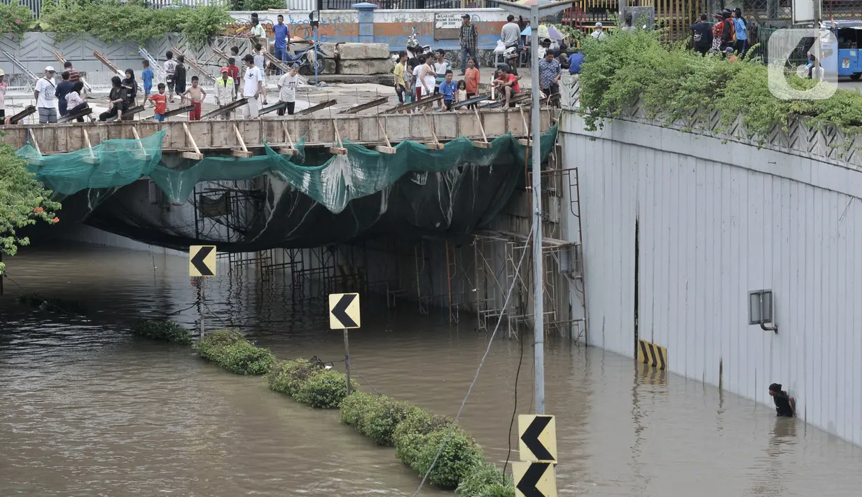 Warga melihat banjir yang merendam Underpass Senen, Jakarta, Selasa (25/2/2020). Hujan deras yang mengguyur Ibu Kota sejak dini hari tadi menyebabkan Underpass Senen terendam banjir setinggi dua meter sehingga mengakibatkan akses Cempaka Putih-Pasar Senen terputus. (merdeka.com/Iqbal Nugroho)