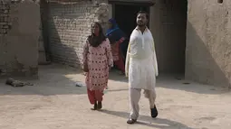Mohammad Ikram berjalan bersama ibunya Rizia Bibi di rumah mereka di sebuah desa dekat kota Samundri, Pakistan, Minggu (25/10/2020). Dia tinggal di kota pedesaan terpencil di provinsi Punjab dan kecacatan fisiknya tidak menghalangi impian masa kecilnya untuk bermain snooker. (AP Photo/Anjum Naveed)