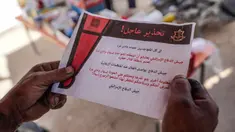 Warga Palestina membaca salah satu selebaran yang dijatuhkan oleh militer Israel di Deir el-Balah di Jalur Gaza Tengah pada tanggal 16 April 2024. (AFP)