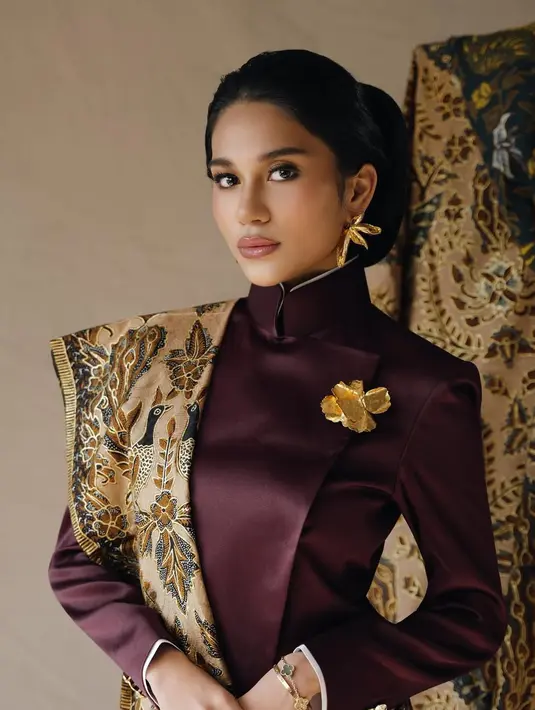 Wajahnya dipulas dengan nuansa makeup bold oleh @vs_makeupstudio. Dengan mengaplikasikan blush on dan lipstik kecoklatan glossy. Rambutnya ditata sanggul klasik khas Jawa. [@azizahsalsha_]