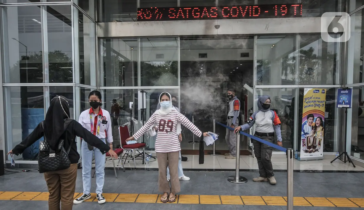 Petugas menyemprotkan disinfektan kepada warga sebelum memasuki ruang vaksinasi Covid-19 di Pasar Ikan Modern Muara Baru, Penjaringan, Jakarta, Kamis (5/8/2021). Vaksinasi massal yang menyasar masyarakat kawasan pesisir ini menargetkan hingga 2.000 peserta tiap harinya. (merdeka.com/Iqbal S Nugroho)