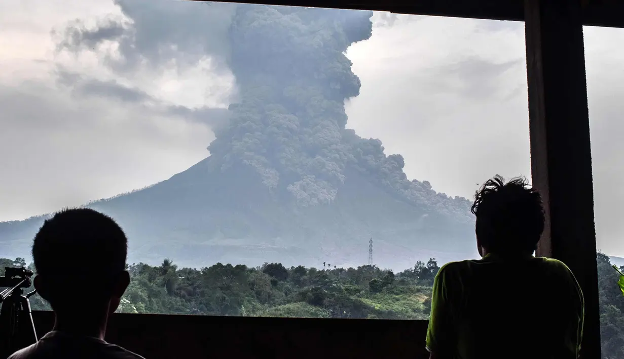 Penduduk desa melihat asap abu vulkanik Gunung Sinabung dari kota Karo (6/4). Gunung Sinabung di Kabupaten Karo, Sumatera Utara, kembali meletus, pada Jumat (6/4/2018) pukul 16.07 WIB. (AFP Photo/Anto Sembiring)