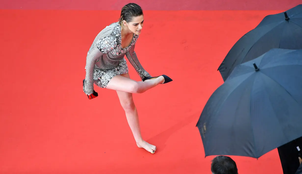 Kristen Stewart melepas sepatunya di karpet merah pemutaran film BlackKkKlansman pada Festival Film Cannes, Prancis, Senin (14/5). Ini merupakan bentuk protes Stewart atas kebijakan panitia yang melarang tamu mengenakan sepatu flat. (AFP/Alberto PIZZOLI)