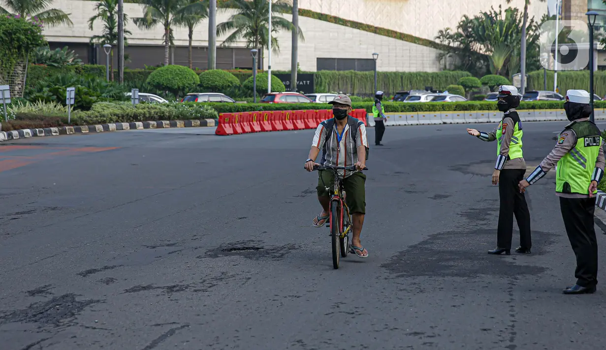 Polisi saat penertiban pesepeda yang keluar jalur di kawasan Sudirman-Thamrin, Jakarta Pusat, Rabu (2/6/2021). Sepeda road bike diperbolehkan untuk melintas di Jalan Sudirman-Thamrin pada hari kerja Senin-Jumat, namun dibatasi dari pukul 05.00-06.30 WIB. (Liputan6.com/Faizal Fanani)