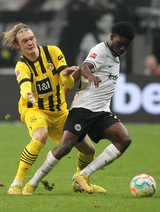 Gelandang Borussia Dortmund, Julian Brandt (kiri) dan gelandang Eintracht Frankfurt, Eric Ebimbe berebut bola pada laga pekan ke-12 Bundesliga Jerman 2022/2023 di Deutsche Bank Park, Minggu (30/10/2022) dini hari WIB. Dengan hasil ini Dortmund berhak naik ke peringkat ketiga klasemen Liga Jerman usai mengoleksi 22 poin hasil 12 pertandingan. (Photo by Daniel ROLAND / AFP)