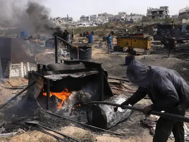 Seorang pria Palestina bekerja di pabrik darurat yang mengekstraksi Bahan Bakar Minyak (BBM) dari plastik daur ulang di Jabalia di Jalur Gaza utara pada 6 April 2025. (BASHAR TALEB/AFP)