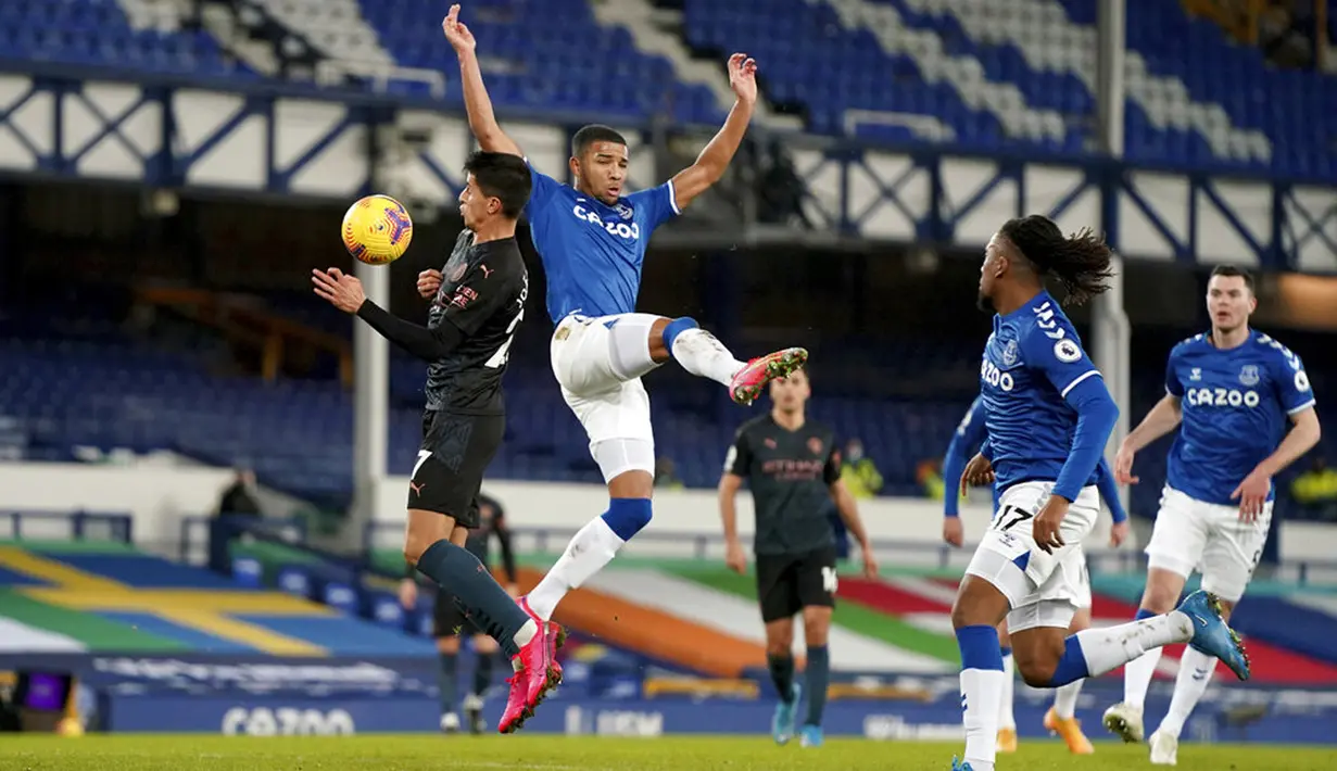 Pemain Manchester City Joao Cancelo (kiri) memperebutkan bola dengan pemain Everton Mason Holgate pada pertandingan Liga Inggris di Stadion Goodison Park, Liverpool, Inggris, Rabu (17/2/2021). Manchester City menang 3-1. (Jon Super/Pool via AP)