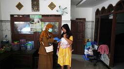 Tenaga kesehatan Siti Nurjanah memberikan vaksinasi campak dalam kampanye dari rumah ke rumah menyusul wabah di Sumenep, Pulau Madura, Jawa Timur, Senin 8 September 2025. (AP Photo/Dita Alangkara)