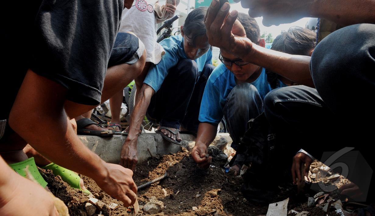 Penemuan batu yang diduga jenis giok di sebuah trotoar memicu warga yang lain untuk mencarinya, Tomang, Jakarta, Sabtu, (9/5/2015). (Liputan6.com/Andrian M Tunay)