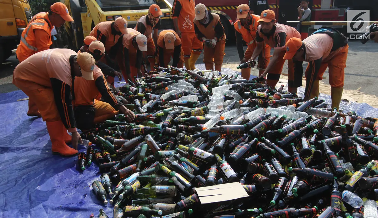 Petugas memusnahkan barang bukti miras dan narkoba di halaman Polsek Palmerah, Jakarta Barat, Senin (14/5). Pemusnahan dilakukan untuk menciptakan suasana kondusif menjelang bulan suci Ramadan. (Liputan6.com/Arya Manggala)